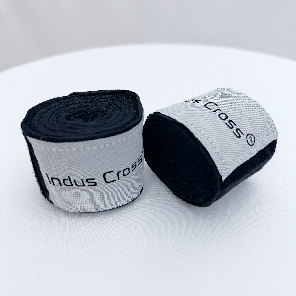 Two rolls of Indus Cross boxing hand wraps on a white surface.