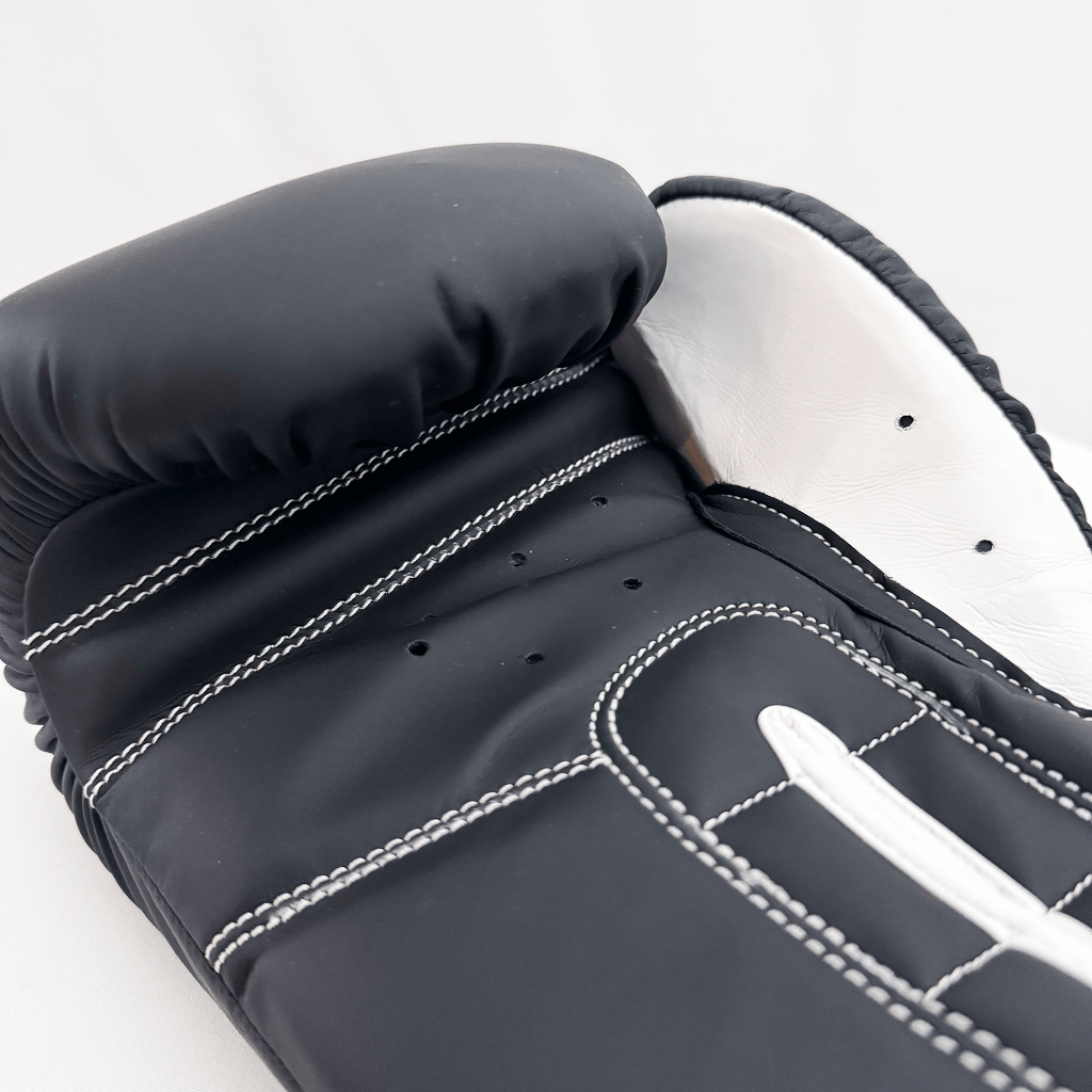 Close-up of a black boxing glove with white stitching on a white background
