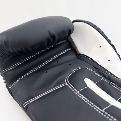 Close-up of a black boxing glove with white stitching on a white background