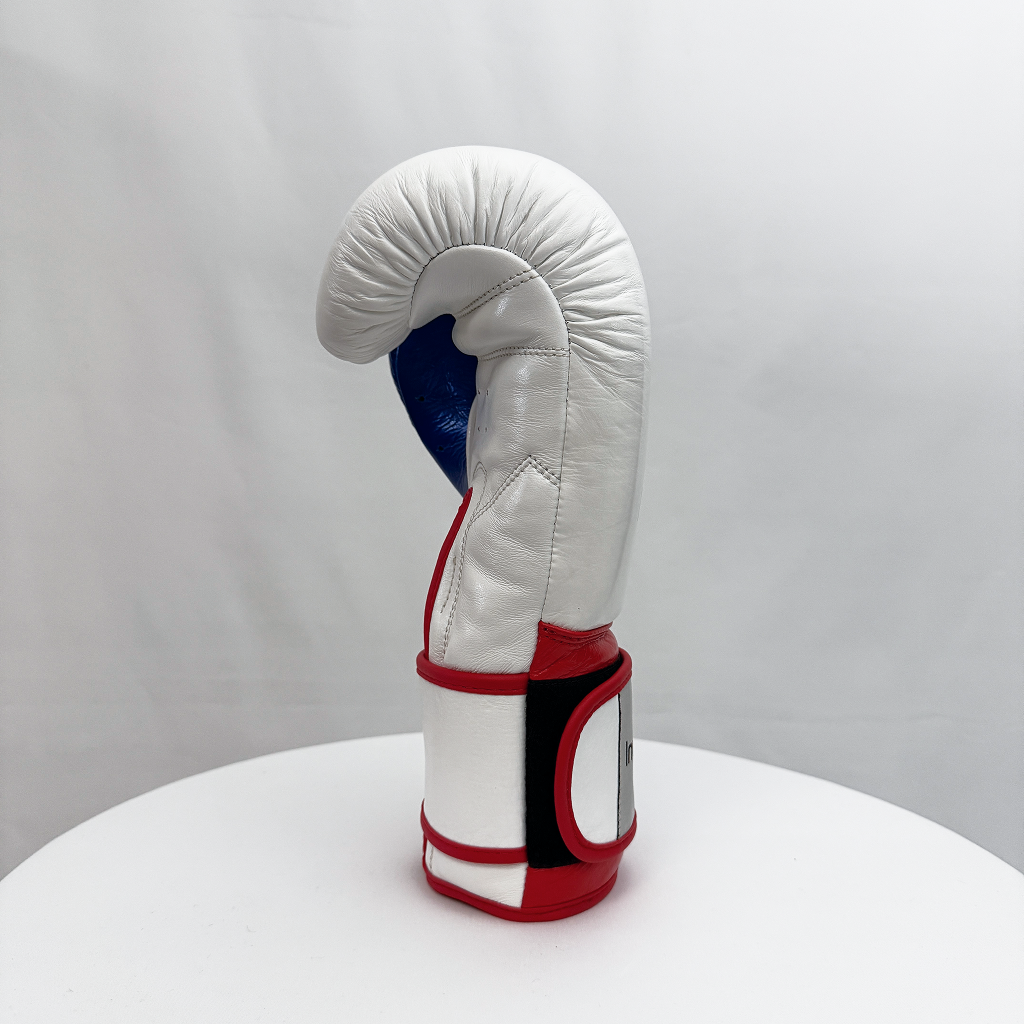 White boxing glove with red and blue accents on a white surface and gray background