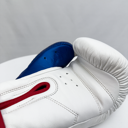 Close-up of a white boxing glove with blue and red accents on a gray background
