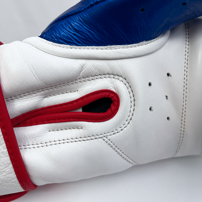 Close-up of a white and blue boxing glove with red accents on a light gray background