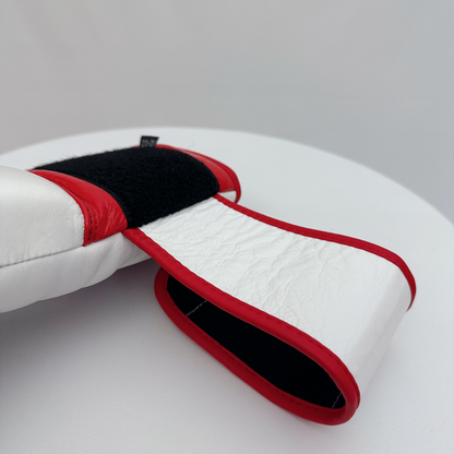 Close-up of a white and red boxing glove's wrist strap on a gray background