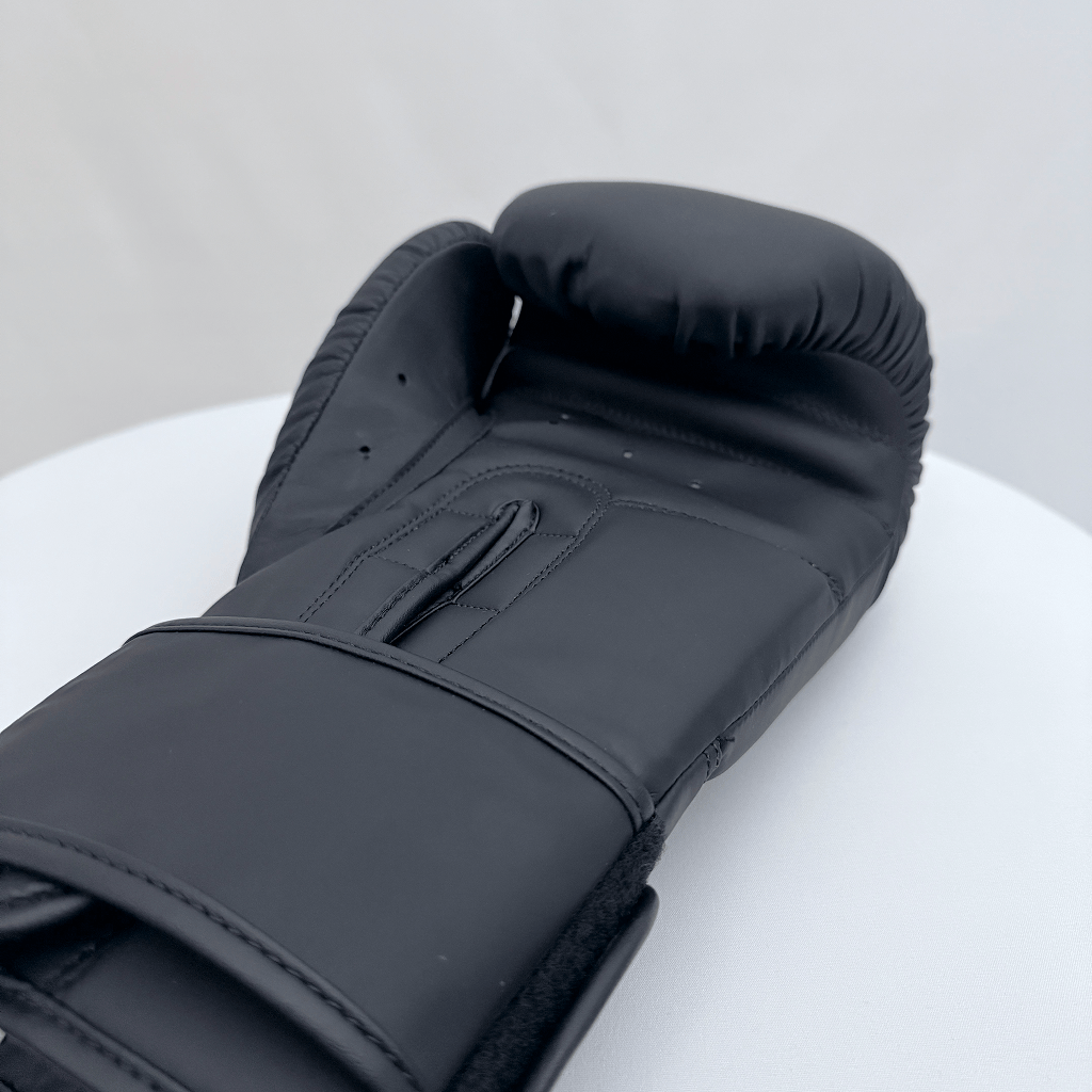 Black boxing glove on a white surface with a gray background