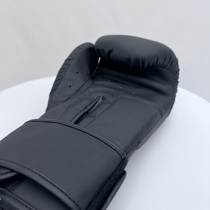 Black boxing glove on a white surface with a gray background