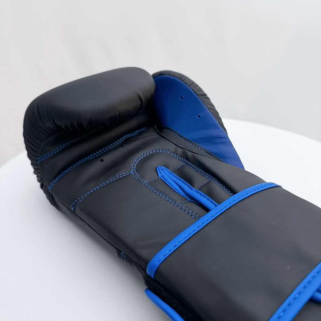 Black and blue boxing glove on a white surface with a light gray background