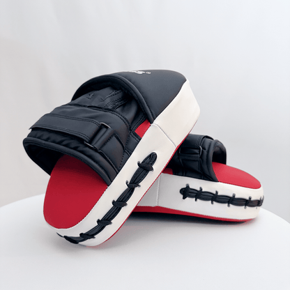 Pair of red and black boxing focus mitts on a white background