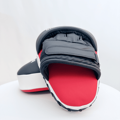Pair of red and black boxing focus mitts on a white background