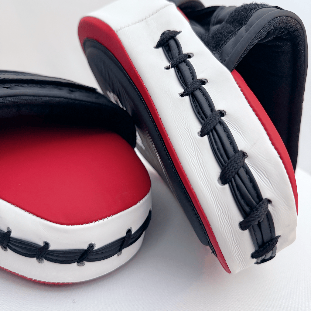 Pair of red and black boxing focus mitts on a white background