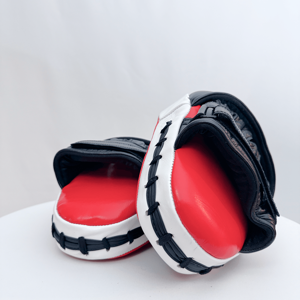 Pair of red and black boxing mitts on a white background