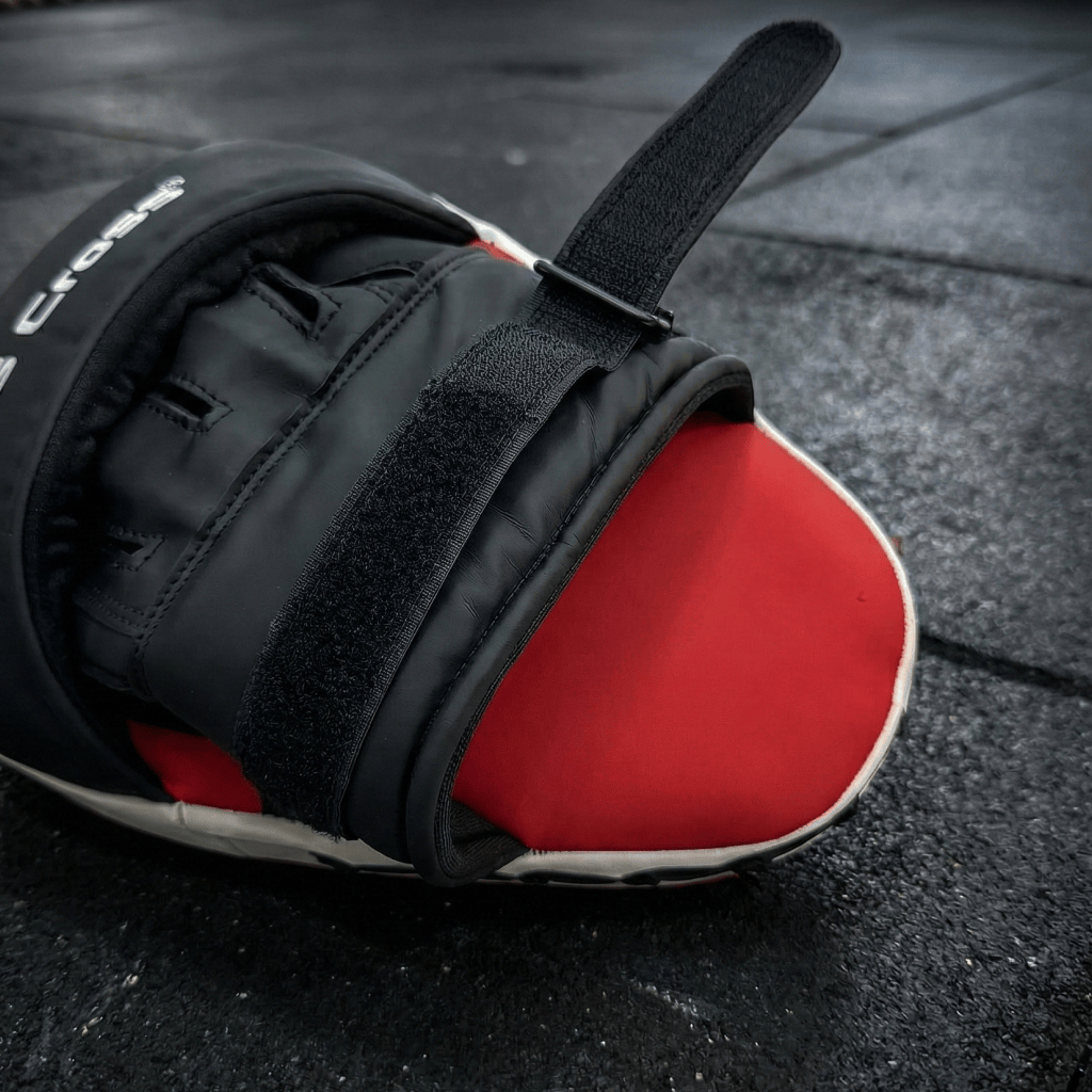Close-up of a black and red Indus cross Ventus-GL Boxing Focus Mitt on a dark surface.