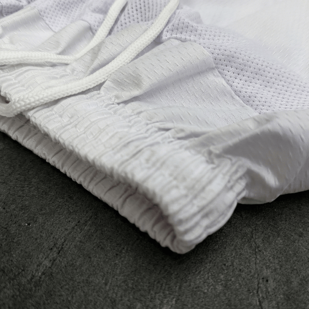 White Indus Cross Lightweight Karate Suit (White Belt Included) with textured fabric on a dark surface.