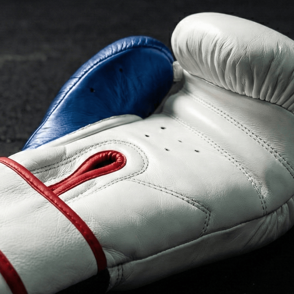 Close-up of a white Indus Cross Vertex Boxing Training Gloves - Genuine Leather boxing showing the inside on a dark background.