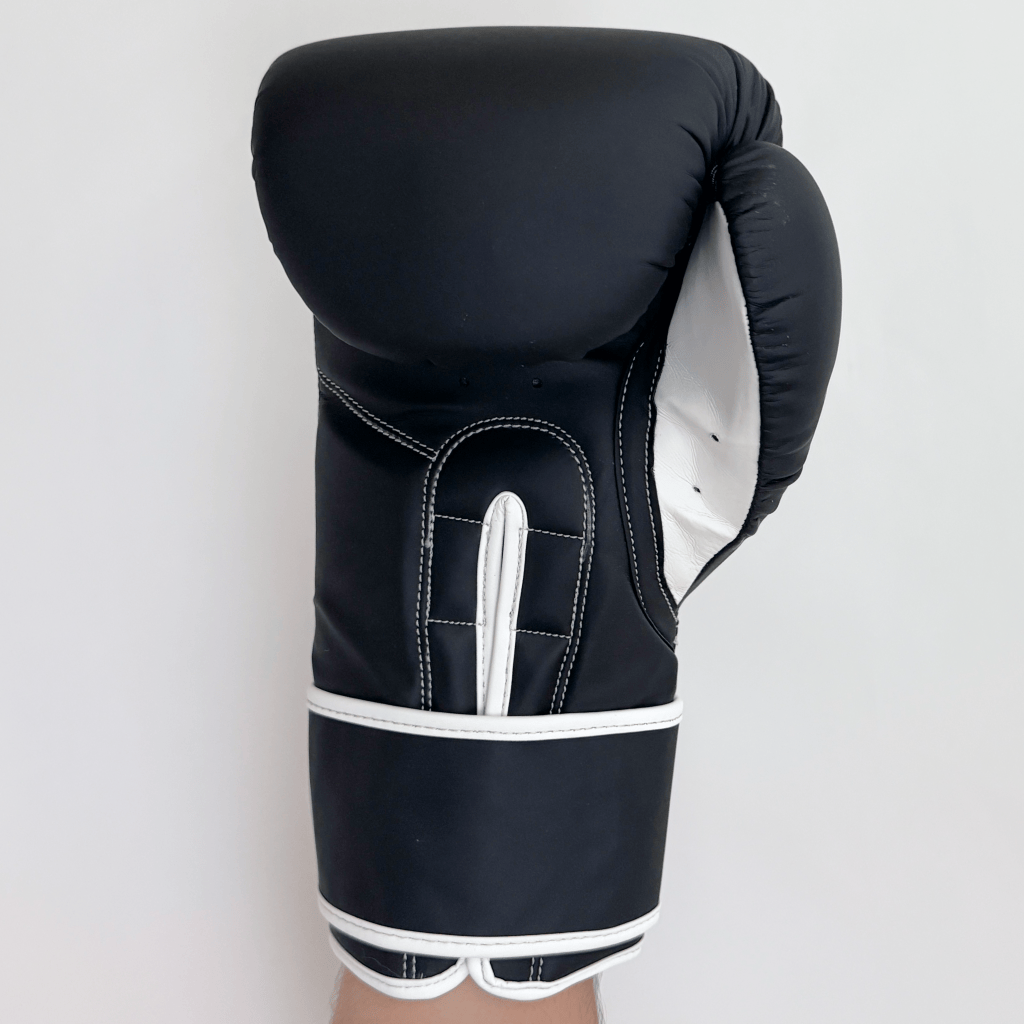 Black boxing glove with white accents on a light gray background