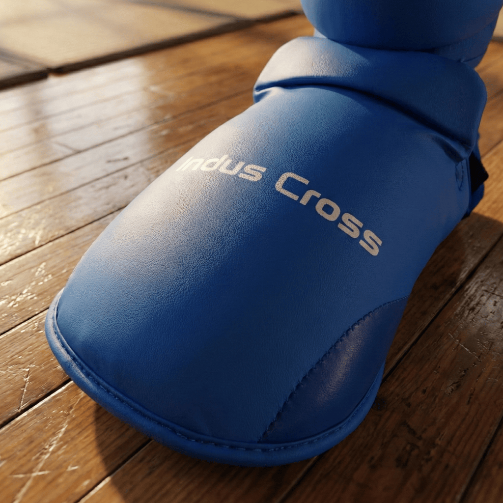 Blue Indus Cross Karate Shin & Instep Guard on a wooden floor.