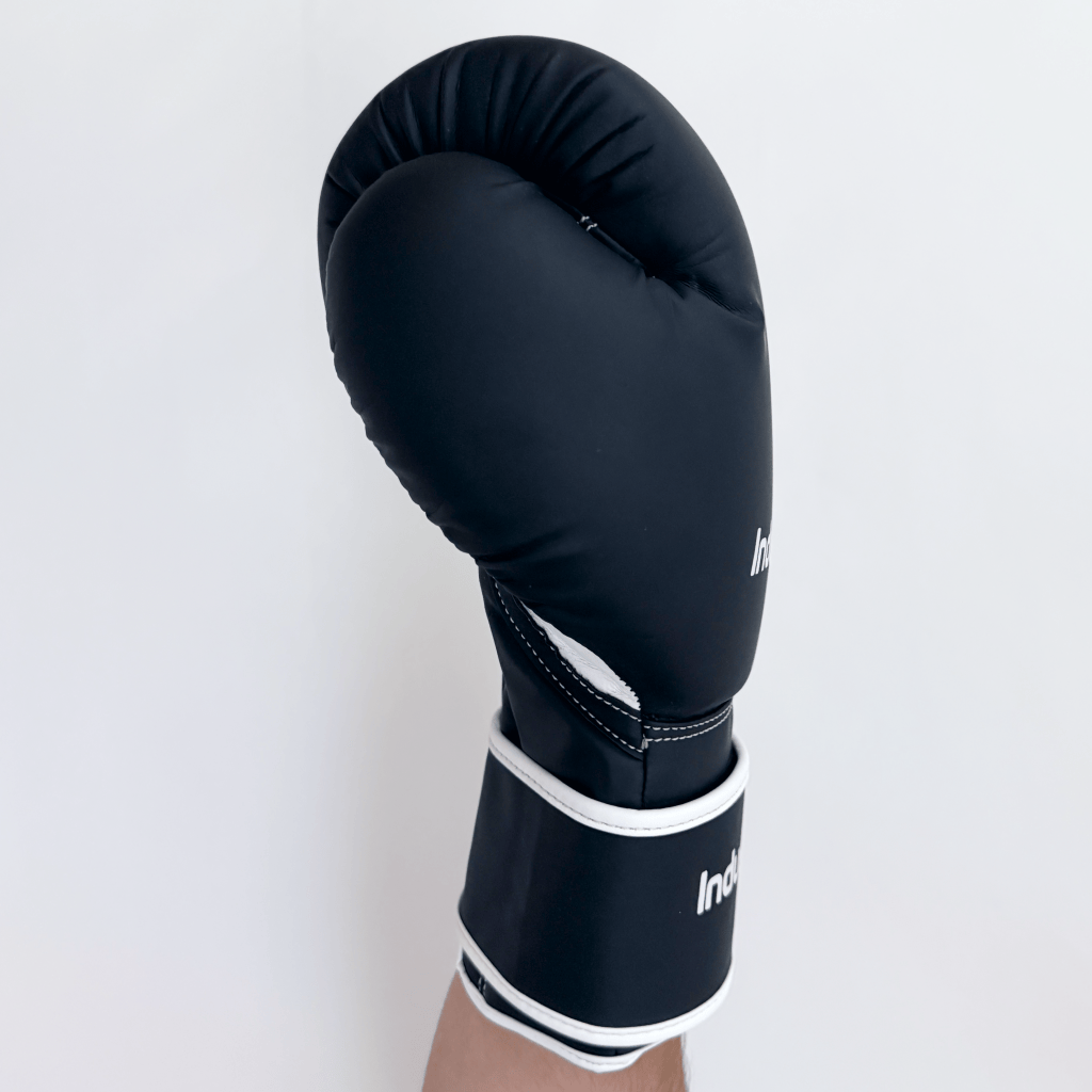 Black boxing glove with white trim on a light gray background