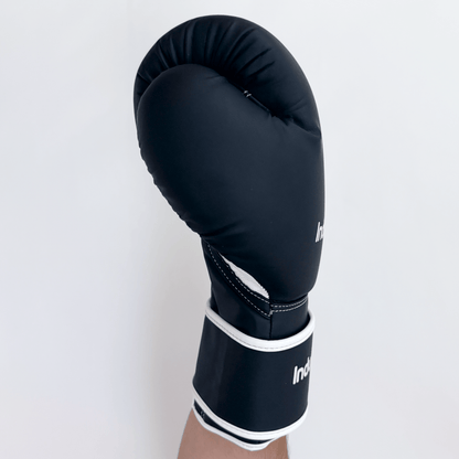 Black boxing glove with white trim on a light gray background