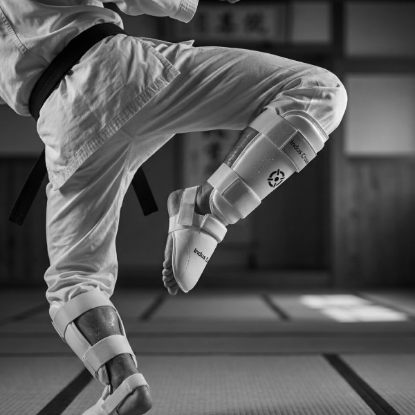 Person in martial arts uniform with protective gear on a blurred dojo background