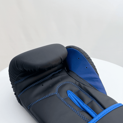 Black and blue boxing glove on a white surface with a light gray background