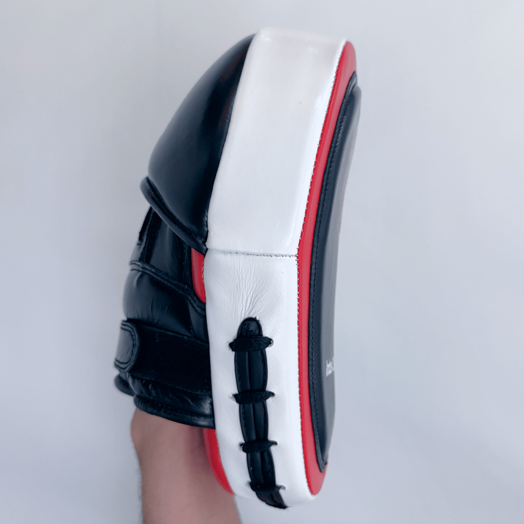 Side view of red and black boxing focus mitts on a white background