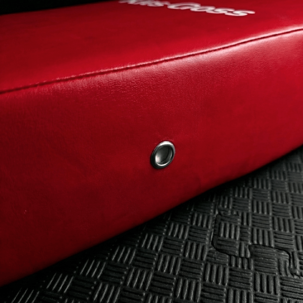 Close-up of a red kick shield with a brand logo on a textured black surface