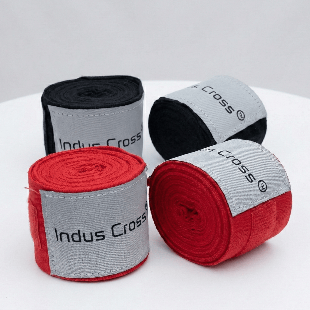 Four rolls of Indus Cross boxing hand wraps in black, and red on a white background.