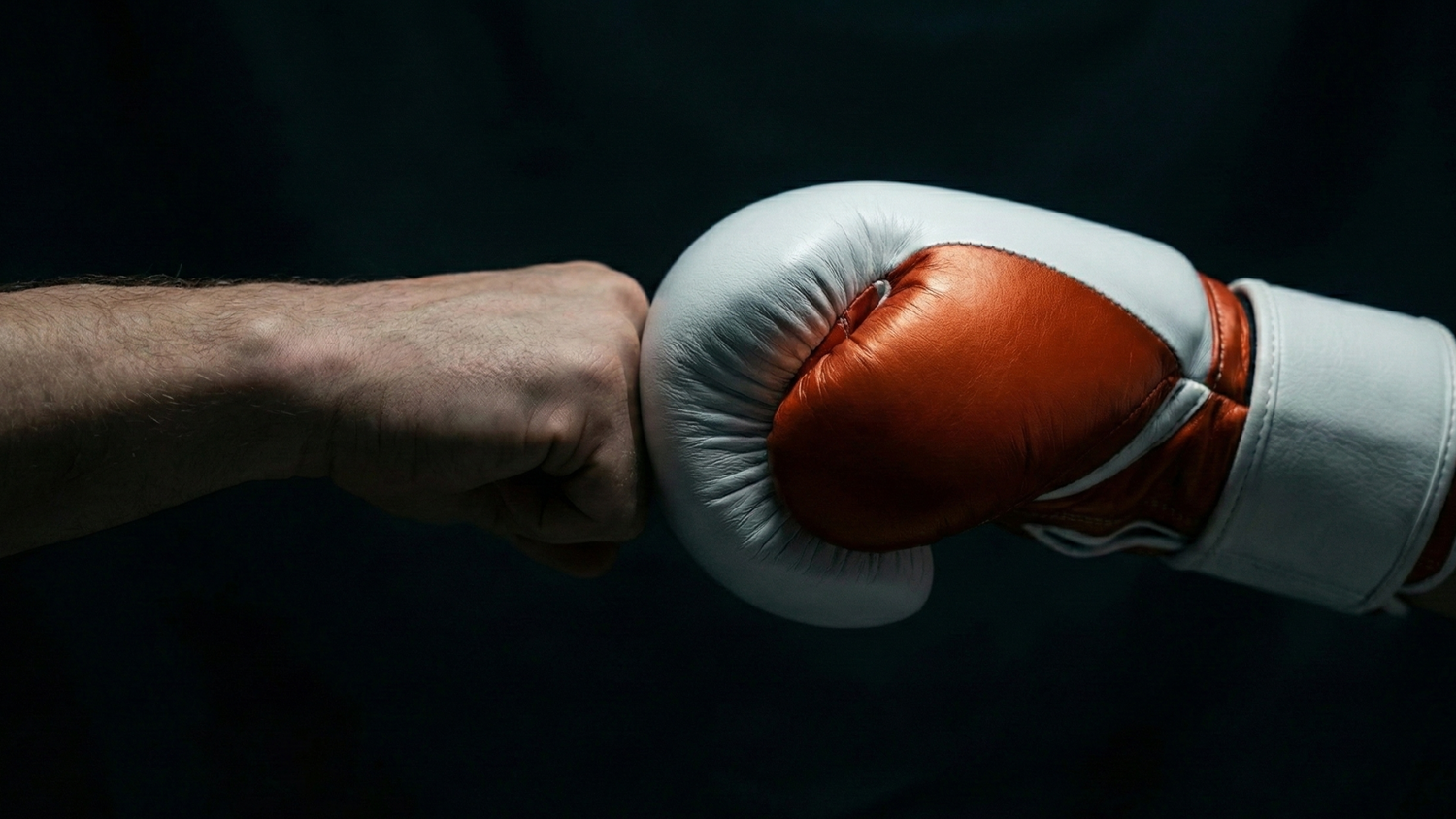 Close-up of a person wearing a red boxing glove against a dark background